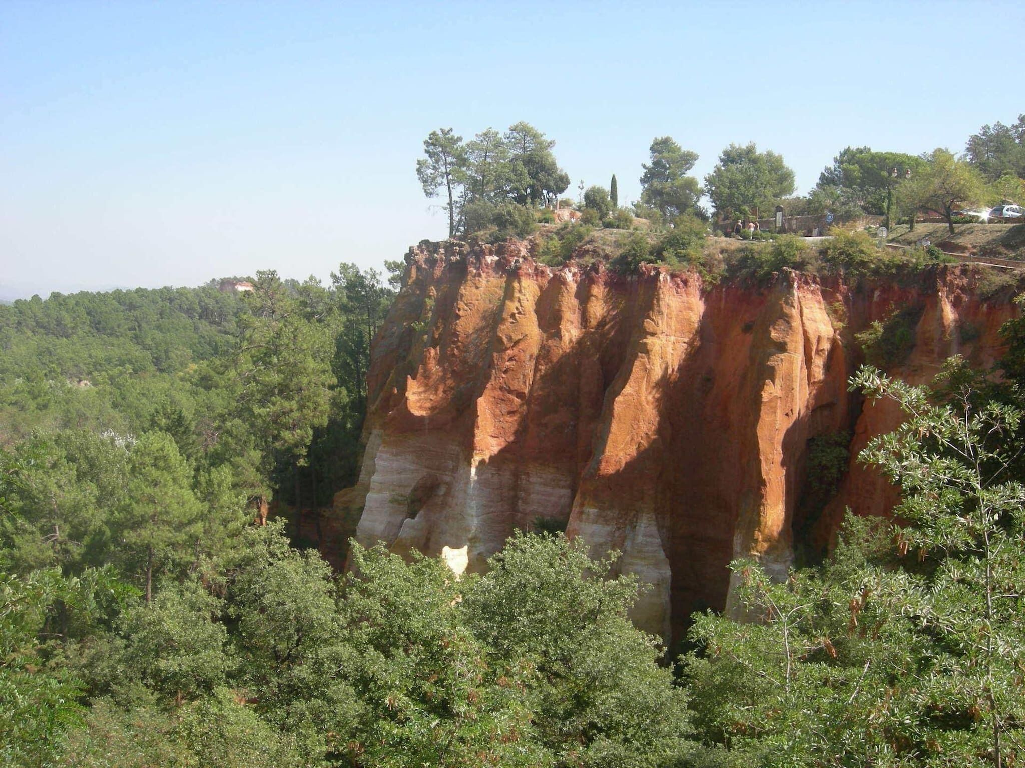 Un paysage naturel caractérisé par une falaise imposante et une forêt dense.