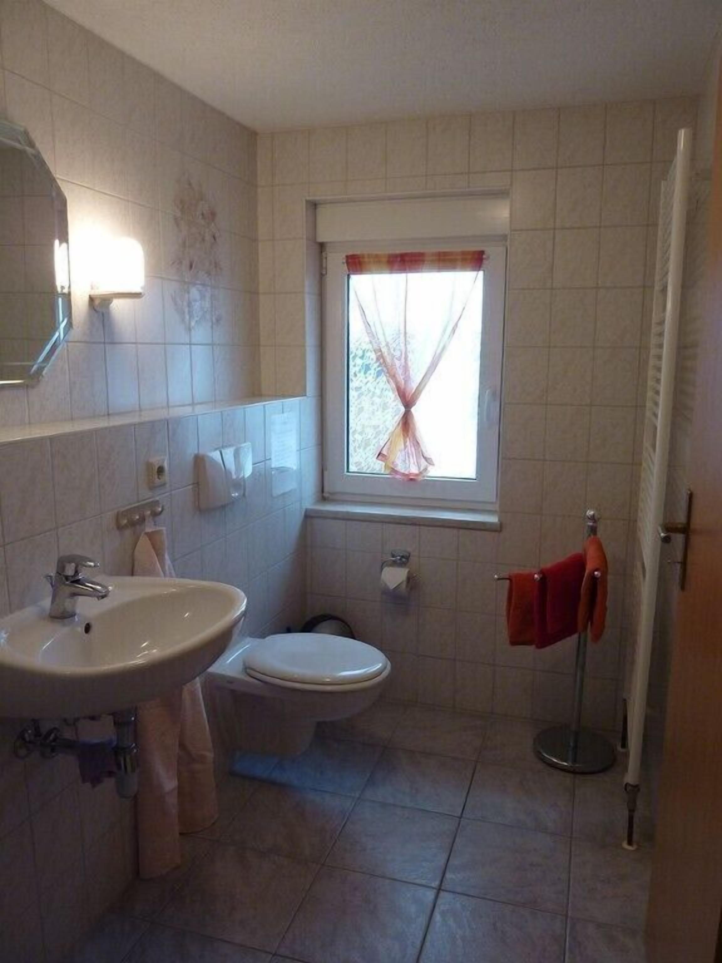 Un baño pequeño con lavamanos, inodoro y ventana.