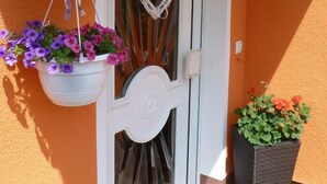 Una puerta con un adorno con forma de corazón, una cesta colgante de flores y un farol.