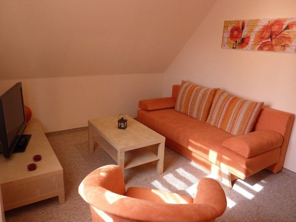 A cozy living room with a sofa, a small table, and a television.