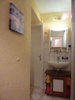 A bathroom with a white sink, a mirror, and a towel rack with folded towels.
