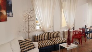 Un salon avec un canapé, une petite table et un arbre décoratif.