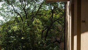 Un balcon donnant sur des arbres et la façade d’un immeuble.