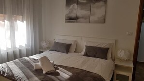 Une chambre à coucher avec un grand lit, deux tables de chevet et un tableau au-dessus du lit.