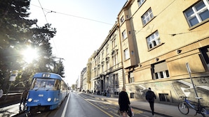 Un tramway sur les rails, une rue avec des piétons et des bâtiments couverts de graffitis.