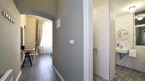Un couloir menant à une salle de bain équipée d’un lavabo, d’un miroir et de carreaux de sol à motifs.