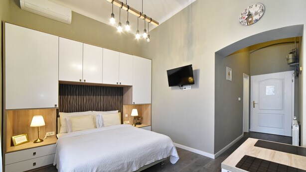Une chambre d’hôtel équipée d’un lit, de lampes de chevet, d’une télévision, d’une horloge et d’un bureau.
