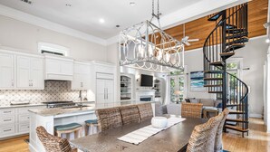A spacious kitchen with white cabinetry, a large island, and a modern chandelier.