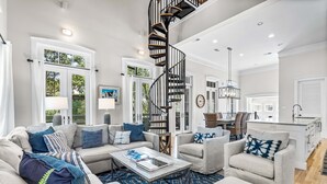 A spacious living room with a modern staircase, a dining area, and a kitchen.