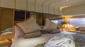 A modern hotel room with a bed, pillows, a bedside table, and a TV. - Riti Yacht (Kalkara)
