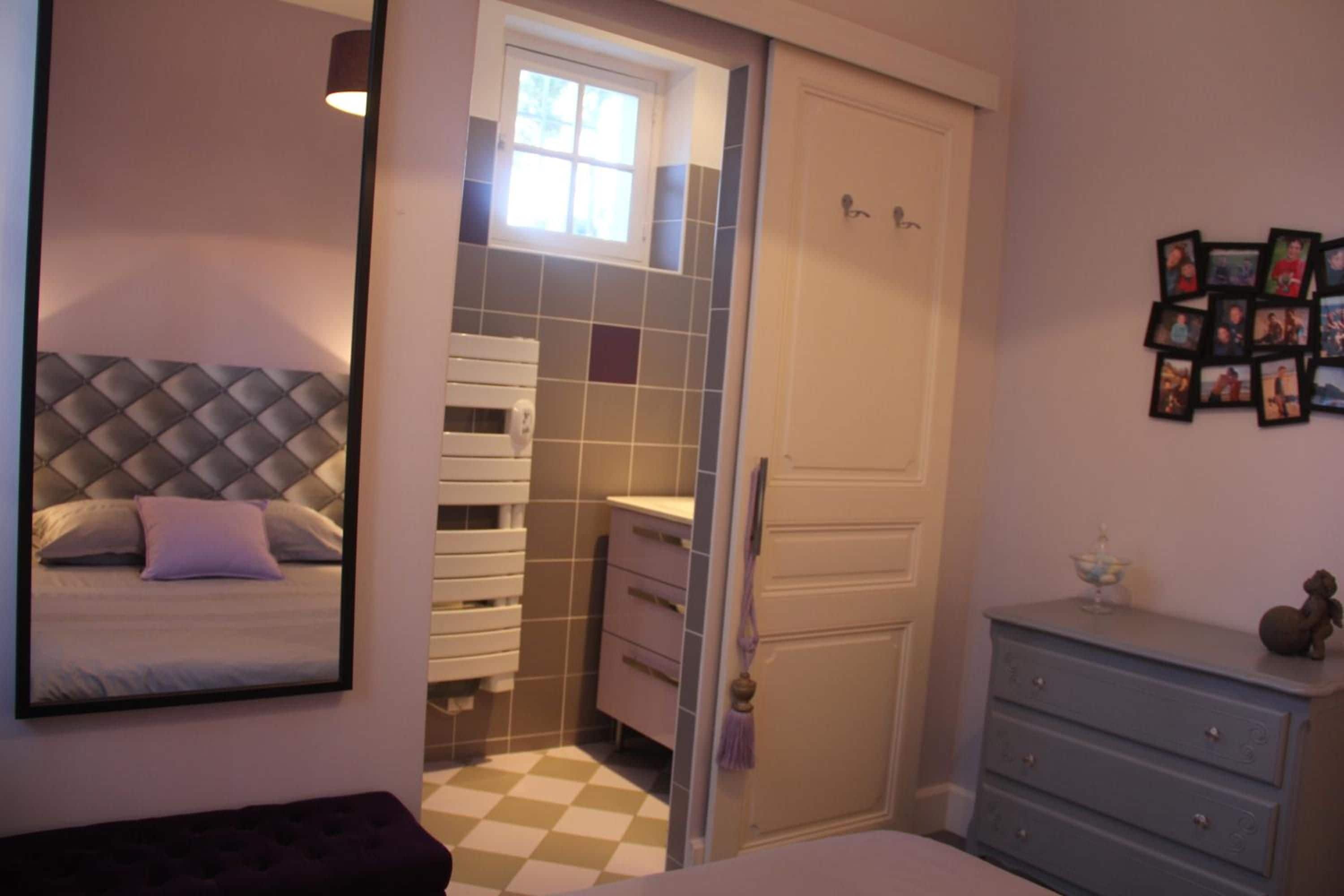 Une chambre à coucher comprenant un lit, une armoire, une commode et un mur orné de photos encadrées.