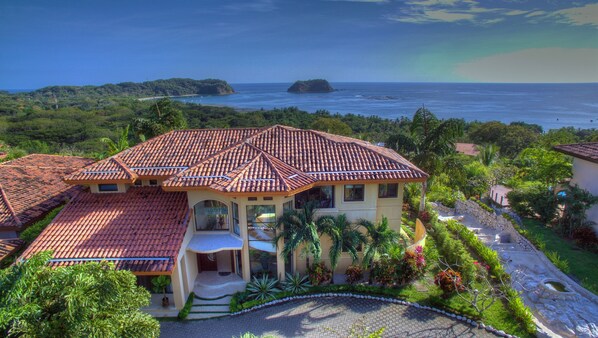 A large house with a tiled roof, surrounded by lush greenery and a view of the ocean. - Luxury Ocean View Villa, Breakfast, Shuttle & 5-Star Service Included ⭐️⭐️⭐️⭐️⭐️ (Samara Beach)