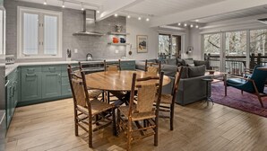 A spacious kitchen with a large island, a dining area with rustic chairs, and a cozy seating area with a sofa and chairs.