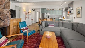 A modern living room with a stone wall, a grey sofa, a blue armchair, and a wooden coffee table.