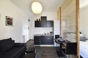 A modern, compact living space with a kitchenette, a dining area, and a sofa.