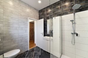 A modern bathroom with a shower, toilet, and a glass-enclosed vanity.