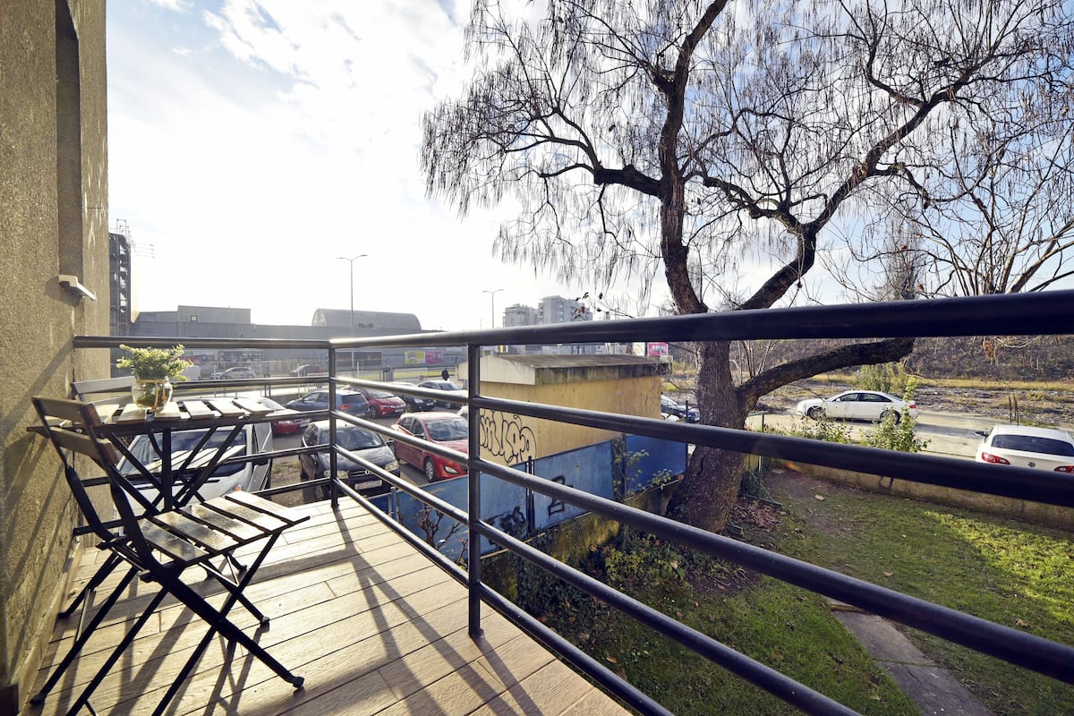 A balcony with a view of parked cars and a tree.