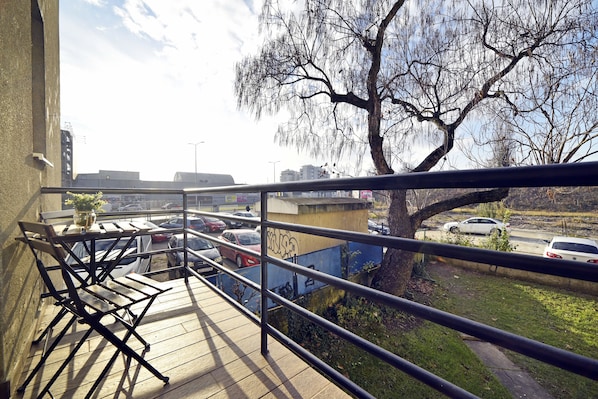 A balcony with a view of parked cars and a tree.