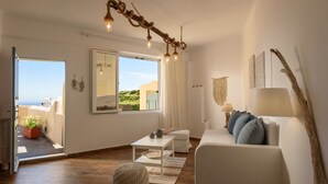 Un saló espaiós amb un sofà blanc, una taula petita i vistes cap a l'exterior a través d'una finestra gran.