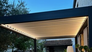 An outdoor patio with a table and chairs, surrounded by potted plants and a pergola. - L'Escale de Mortagne (Thairé)