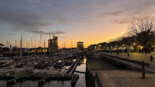 A marina with boats docked, a castle-like structure, and a paved walkway along the water. - L'Escale de Mortagne (Thairé)
