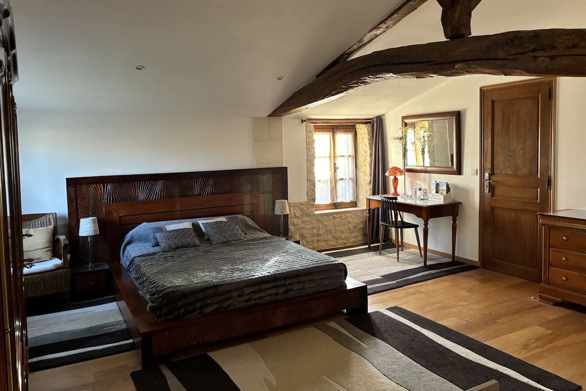 A bedroom with a wooden bed, a desk, and a wardrobe.