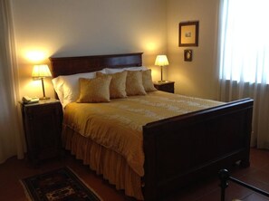A neatly made bed with a wooden headboard, two bedside lamps, and a framed picture on the wall. - Agriturismo La Casa In Collina (Canelli)