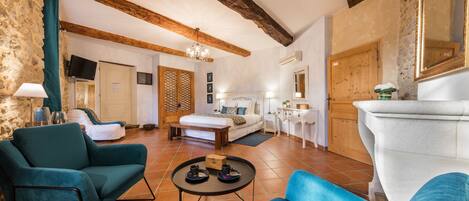 A cozy room with a bed, two sofas, a small table, and a large white fireplace.