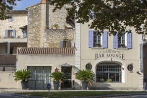 A building with a sign reading "L'Alchimiste Bar Lounge". - Hôtel L'instant Sévigné (Grignan)
