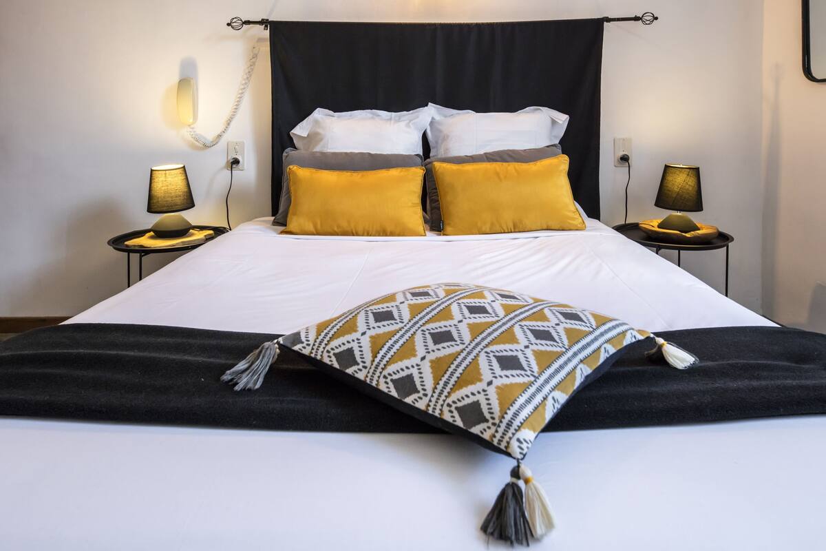 A neatly made bed with a black and white headboard, two bedside lamps, and a patterned throw pillow.