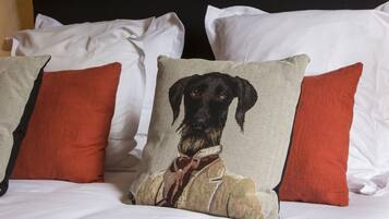 A bed with white linens and multiple pillows, including a pillow with a dog illustration.