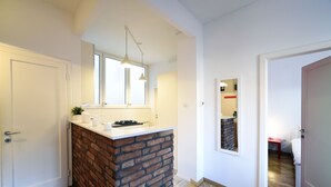 A modern kitchen with a brick island, white countertops, and pendant lighting. - First Choice Centar Apartments (Zagreb)
