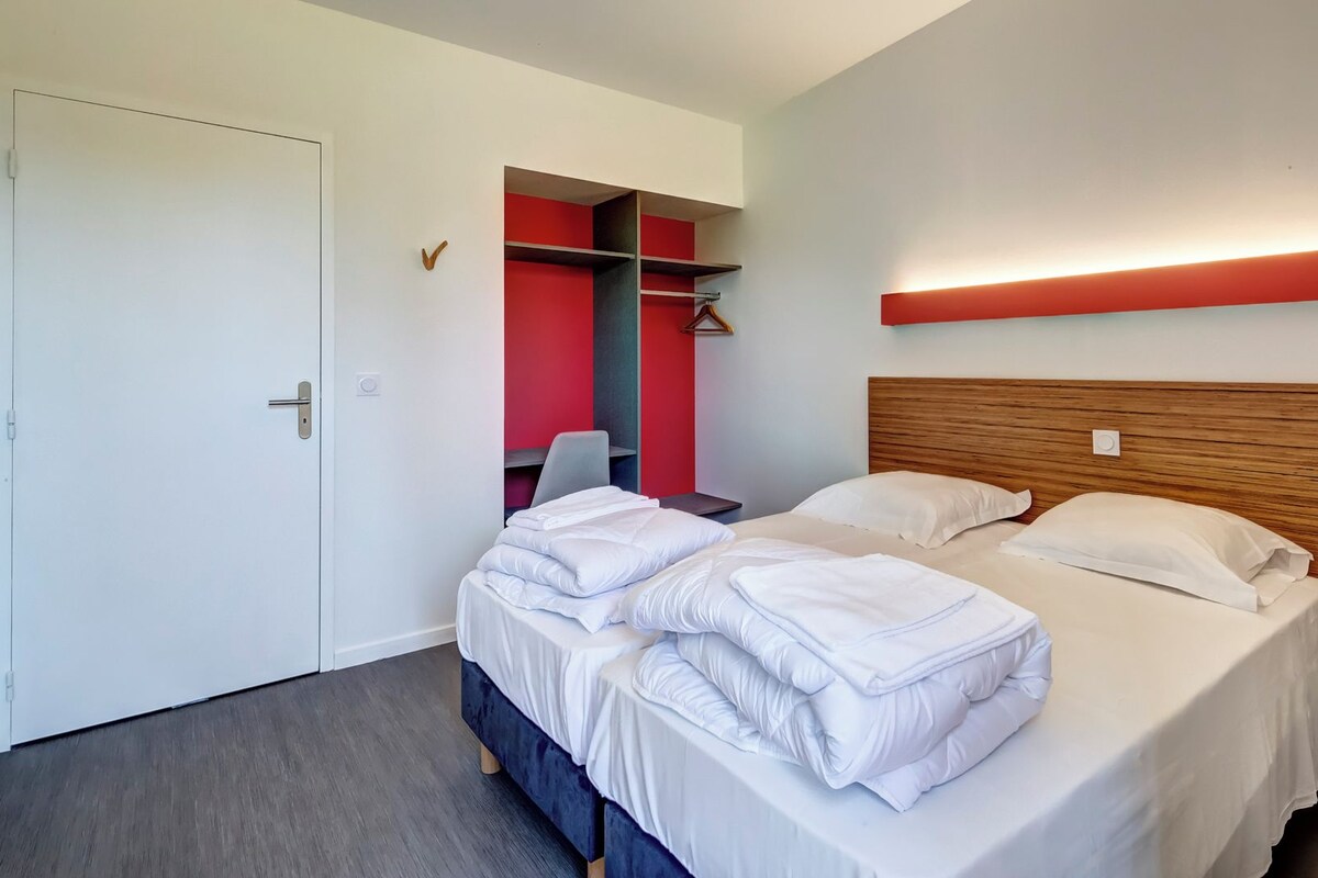 Une chambre d’hôtel avec un grand lit, une armoire et un bureau.