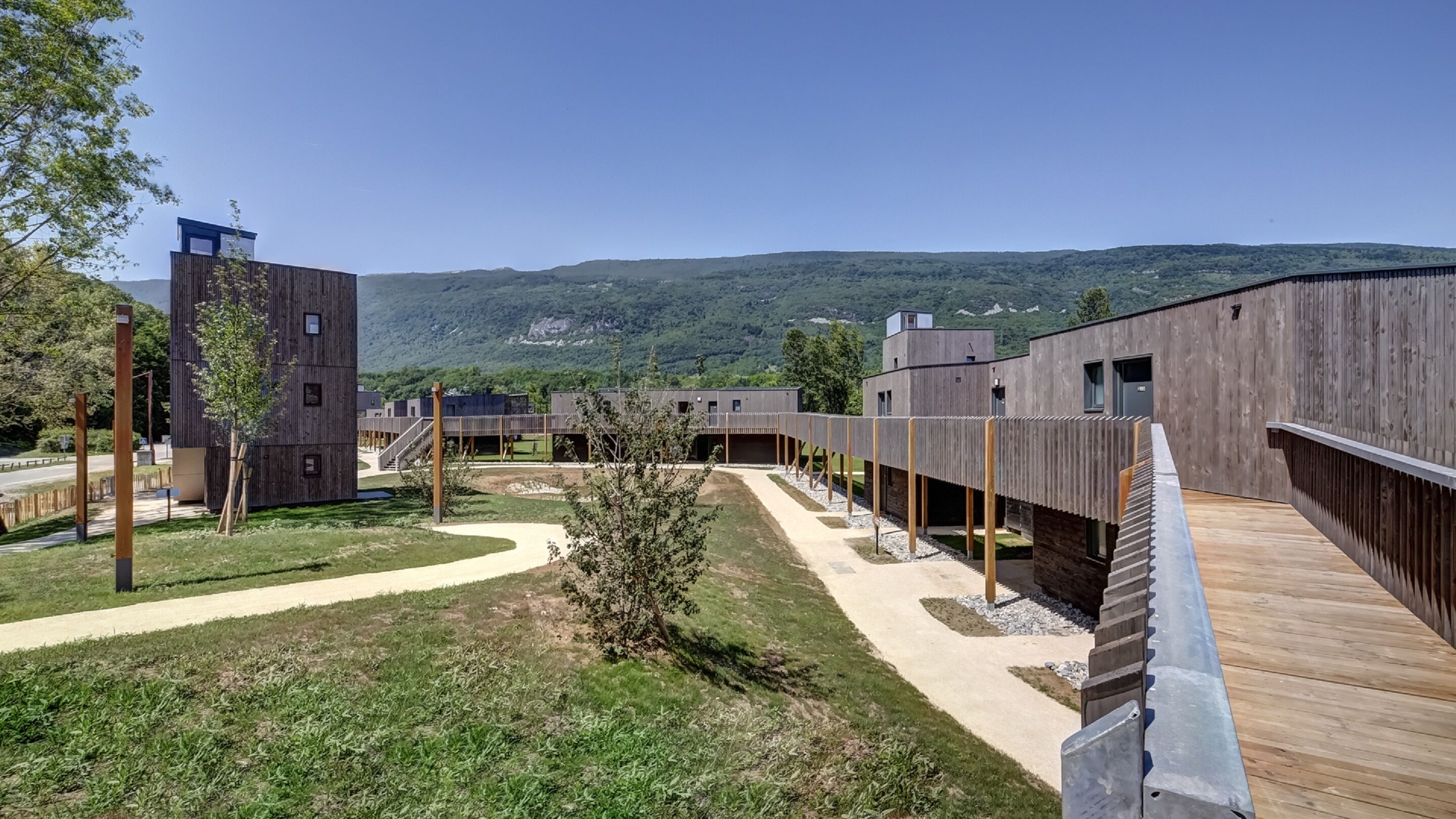 A modern building complex with a wooden deck and a clear view of the surrounding landscape.