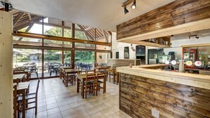 Un café avec des meubles en bois, de grandes fenêtres et un coin bar.
