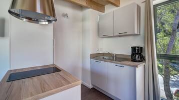 Una cocina moderna con armarios blancos, encimera de madera, campana extractora de acero inoxidable y una cafetera.