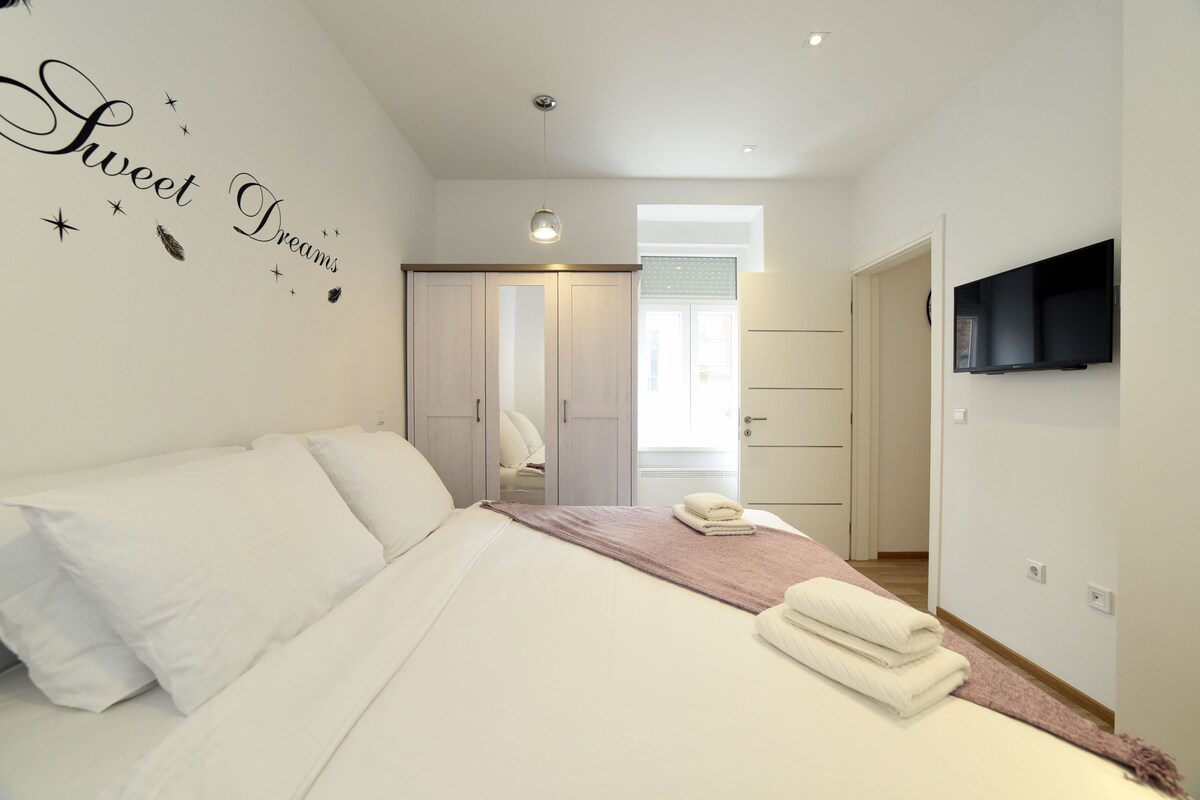 A bedroom with a bed, a TV mounted on the wall, and a wardrobe.
