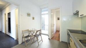 Cozinha moderna com fogão embutido, área de refeições com mesa e cadeiras e vista para a varanda.