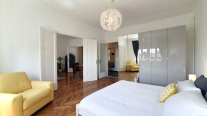 Quarto moderno com uma cama grande, uma poltrona amarela e um closet espaçoso.