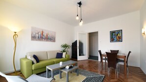 Uma sala de estar moderna com um sofá verde, uma mesa de jantar com cadeiras, uma mesa de centro e um vaso com planta.