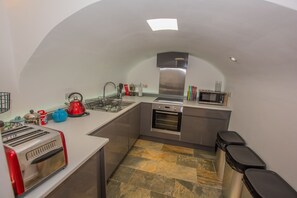 A compact kitchen with a built-in oven, a microwave, and a kettle.