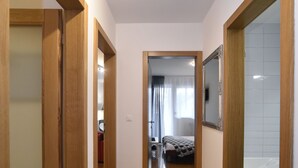 A hallway with wooden flooring and doors leading to a bedroom and bathroom. - Botanic Apartment (Zagreb)