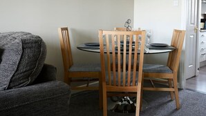 Un coin repas avec une table ronde, quatre chaises en bois et un canapé gris.