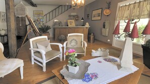 Un salón acogedor con una escalera de madera, un mostrador de recepción y vistas al exterior.