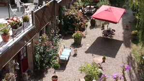 Un patio con mobiliario exterior, plantas en macetas y sombrillas.