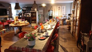 Un comedor con una larga mesa dispuesta para una comida, rodeada de sillas rojas.