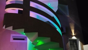 A modern building with a spiral staircase illuminated by multicolored lights. - Dar Lebharr (Kelibia)