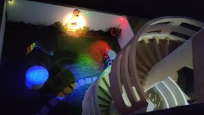 A spiral staircase with a railing, surrounded by a garden with colorful lights. - Dar Lebharr (Kelibia)