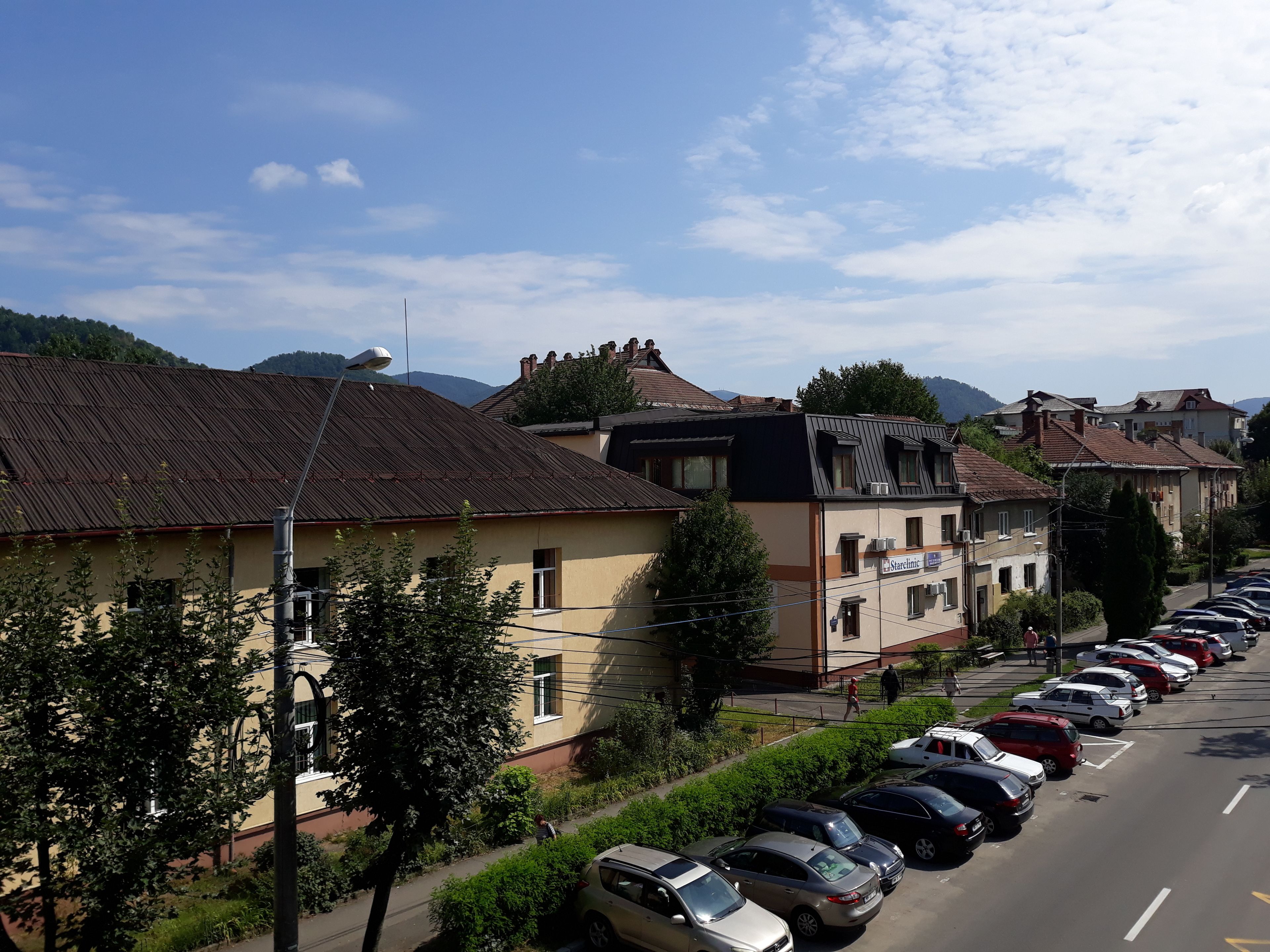 A street view with parked cars, buildings, and a pedestrian.