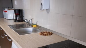 A kitchen with a stainless steel sink, a coffee maker, and a dish soap dispenser.